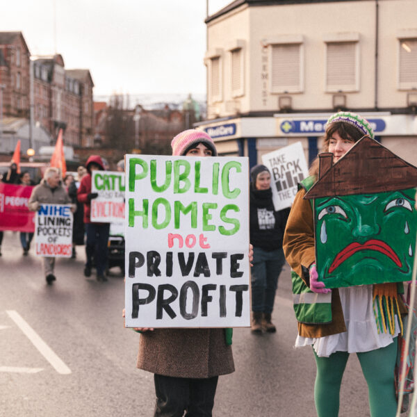 Gníomhaí tithíochta ag a bhfuil comhartha a léann 'tithe poiblí seachas brabús príobháideach'